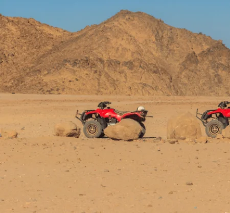 ATVs parked in desert landscape with mountains.
