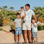 Family posing together in a sunny location in Egypt, with palm trees in the background.