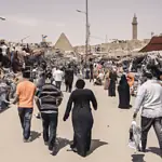 Bustling outdoor market near ancient pyramid and minaret.